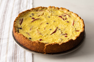 Delicious sweet cheese pie with apples and cranberries, fruit and berry curd pie on a white background with a kitchen towel