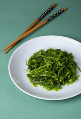 Chuka wakame, Japanese seaweed salad in sesame sauce on a white plate and gray background. 
