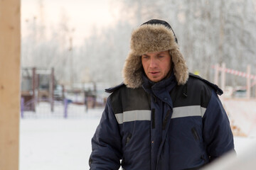 Portrait of a fitter in a blue jacket at a construction site