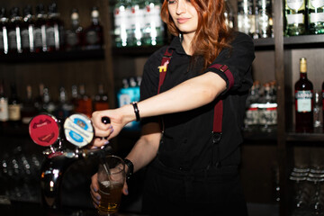 Fototapeta na wymiar Portrait of attractive female bartender tapping beer in pub, focus on hands holding beer