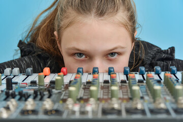 The girl looks out of the music mixing console looking at the camera.