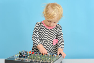 A little girl pushes buttons on a music mixing console.