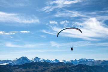 A tandem hang glider flying over the mountains.