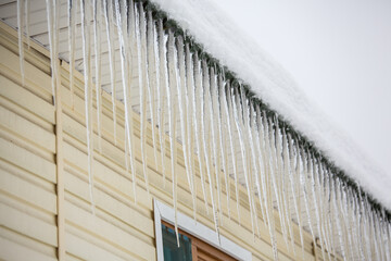 Icicles hang from the roof of a house in winter