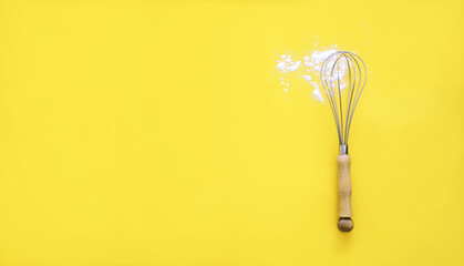 Obraz premium Whisk with wooden handle and white wheat flour on yellow background. Cooking utensil, egg beater mixer whisker . Flat lay banner background.