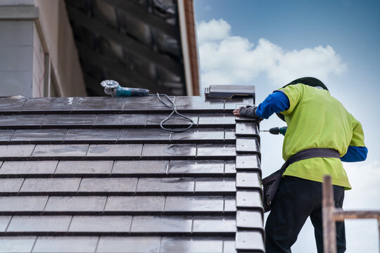 Construction Worker Install Install New Ceramic Tile Roof, Roofing Tools, Electric Drill Used On New Roofs On Construction Site.