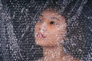 Asian thai woman behind plastic wrap with eye on a hole.