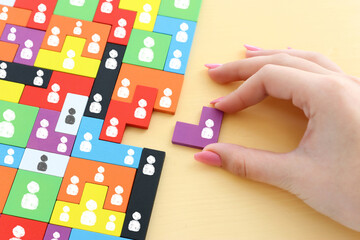 image of tangram puzzle blocks with people icons over wooden table ,human resources and management...