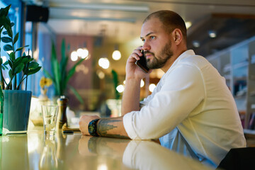 Pensive man talking on phone in cafe