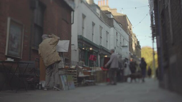 An artist painting on a narrow street in London