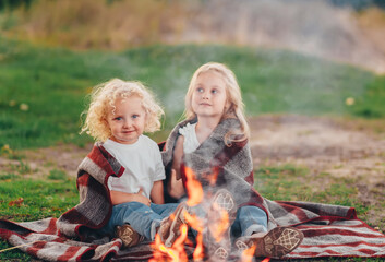 Two sweet little girl, sitting around the campfire.