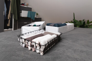 Vertical storage of clothing. Sorted clothes in baskets and shelves in a modern bedromm. Cleaning concept.