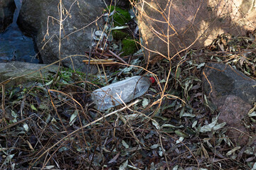 Naklejka na ściany i meble environmental pollution concept, old plastic bottle among grass