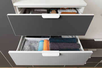 Vertical storage of clothing. Sorted clothes in baskets and shelves in a modern bedromm. Cleaning...