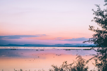 long exposure vanilla colorful sky and  lake reflection with mountains in the background. blurred wild grass blowing in the wind on foreground