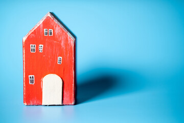 Obraz na płótnie Canvas Wooden toy house on a blue background. Real estate, construction, rental housing concept.