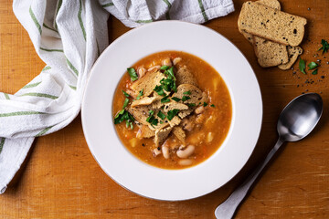 Bowl of tomato lentils soup with beans on wooden board