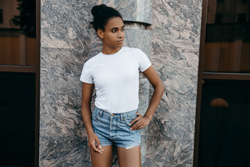 portrait of attractive afro american woman on shorts and t-shorts at gray background 