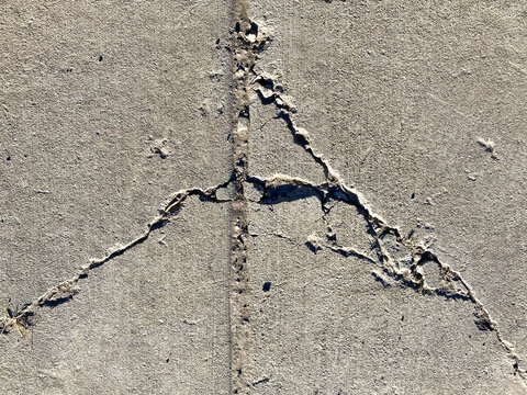 Close Up View Of Concrete Sidewalk Cracks Damage In Natural Sunlight Showing Deep Shadows