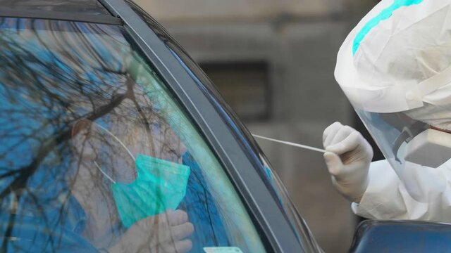 Medical worker in PPE performing drive-thru COVID-19 test