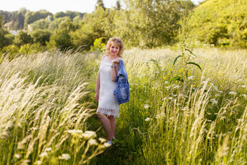 Young woman in blooming near the tree. Spring story. Romantic look with white lace dress. Happy girl in beautiful spring day. Pretty slim blonde woman, caucasian. Portrait