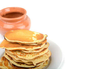 Breakfast.A stack of pancakes in a plate and a pot of honey on a white isolated background.Free space.Space for text, horizontal view.