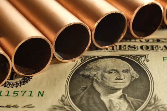 Close up of copper pipes and United States dollar. Commodity value and trading concept.