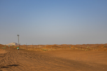 Obraz premium Desert dunes at Al Awir desert near Dubai with buggy vehicle at sunset light. Dubai, United Arab Emirates, Middle East.