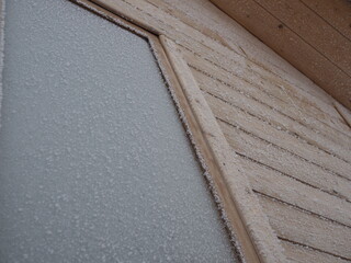 Corner of a wooden house covered with frost, outdoor shot