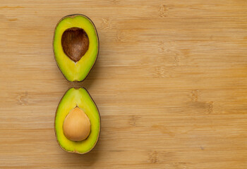 Two cut half avocados with unique arrangement on bamboo cutting board, top view image, space for...