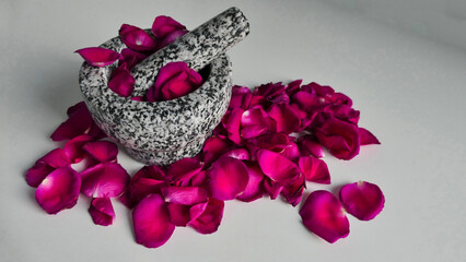 perspective of granite mortar with pestle between rose petals