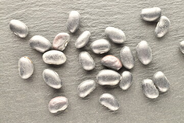 Fototapeta na wymiar Uncooked organic, black dried beans, close-up, on a slate board.