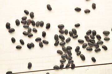 Uncooked organic, black dried beans, close-up, on a wooden table.