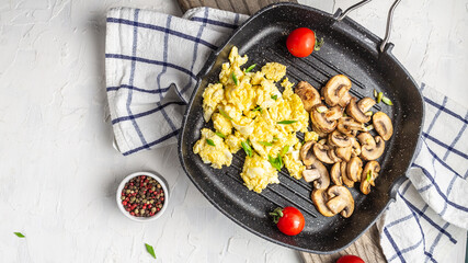 Close up of scrambled eggs with champignon mushrooms in frying pan