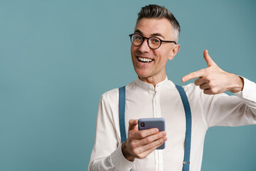 Happy grey-haired man holding and pointing finger at cellphone