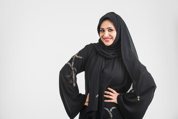 Beautiful woman from Dubai posing on colored background with traditional abaya.