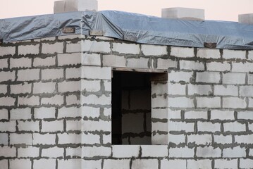 Fototapeta na wymiar wall of an unfinished house of white bricks with an empty one window
