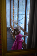 baby stands by the window in winter