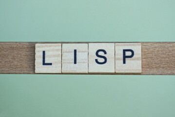gray word lisp made of wooden square letters on green background - obrazy, fototapety, plakaty