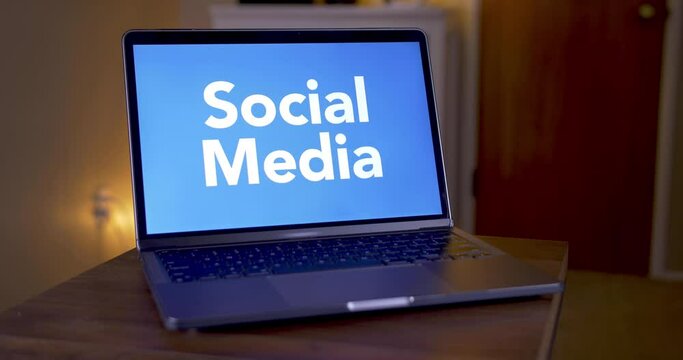 A man opens and closes a laptop showing a generic social media logo. Social media platforms came under scrutiny after the Washington riots of 2021.  	