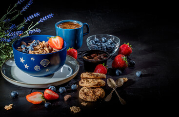 Traditional healthy breakfast foods and drinks - oats, granola, yoghurt, toasts, cereal, croissants, with fruit, berry and coffee on dark background. Diet food or healthy food in the morning