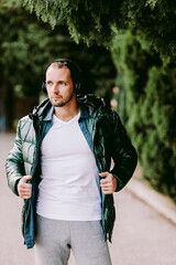 man wearing white t-shirt and jacket mockup and listen to music. Male in blank white t-shirt v collar and shirt and headphones, front view outdoors. Design men t shirt template and mock-up for print 