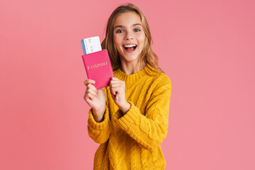 Happy beautiful blonde girl smiling while holding passport with tickets