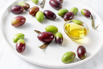 Fresh green and black olives and a oil bowl on a plate