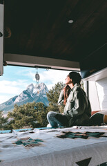 image of a young brunette woman, stretched out inside a camper van, looking towards Pedraforca...