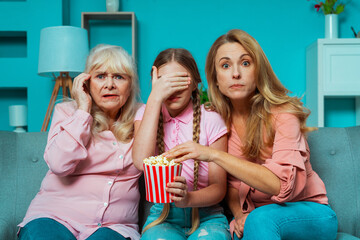 Fototapeta premium Cinematic portrait image of grandmother, mother and grandaughter sitting on the couch