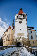 Medieval renaissance water castle with half-timbered tower with snow in winter sunny day, Historic Romantic chateau Blatna near Strakonice in southern Bohemia, Czech Republic