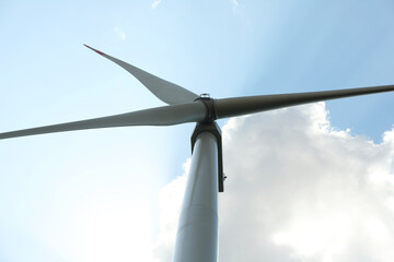 Modern wind turbine against blue sky, low angle view. Energy efficiency