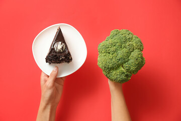 Top view of woman choosing between cake and healthy broccoli on red background, closeup