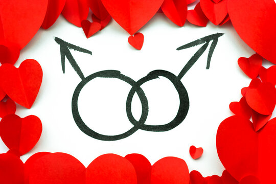 Valentine's Day background. Red paper hearts are lined around the edge against a white background inked with the signs of mars. Men signs. Gay couple.
